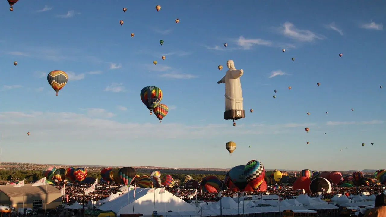 Hundreds of hot air balloons lifting off at Balloon Fiesta Park with the Sandia Mountains behind