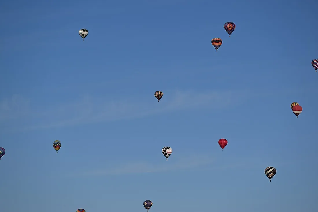 Colorful hot air balloons rising together during a Balloon Fiesta mass ascension