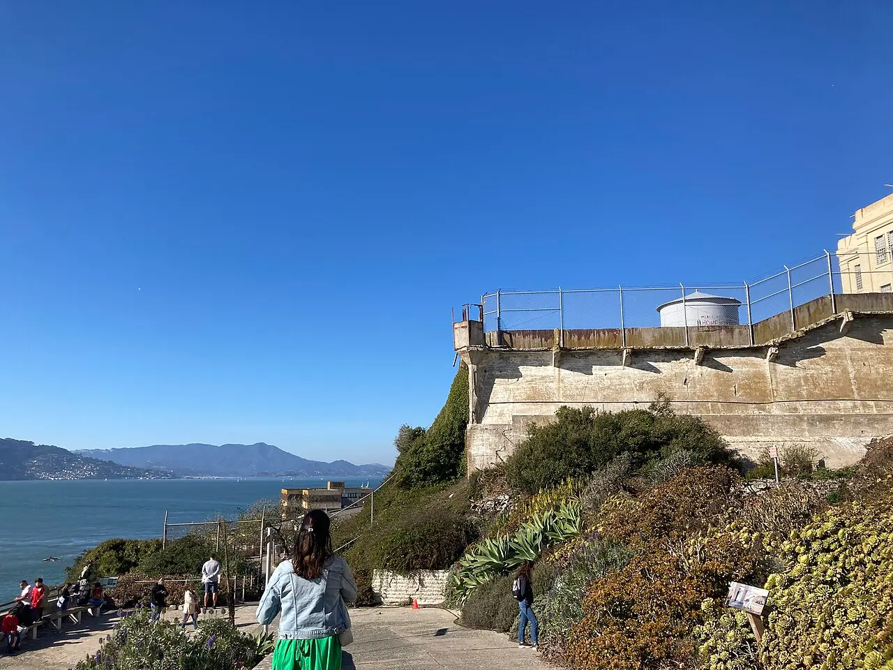 Visitors walking up a terraced, sloped path from the Alcatraz dock toward the cellhouse buildings