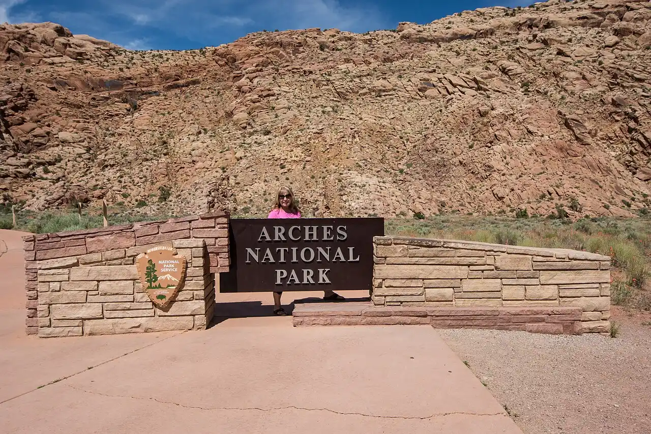 Wooden Arches National Park entrance sign against red rock and blue sky