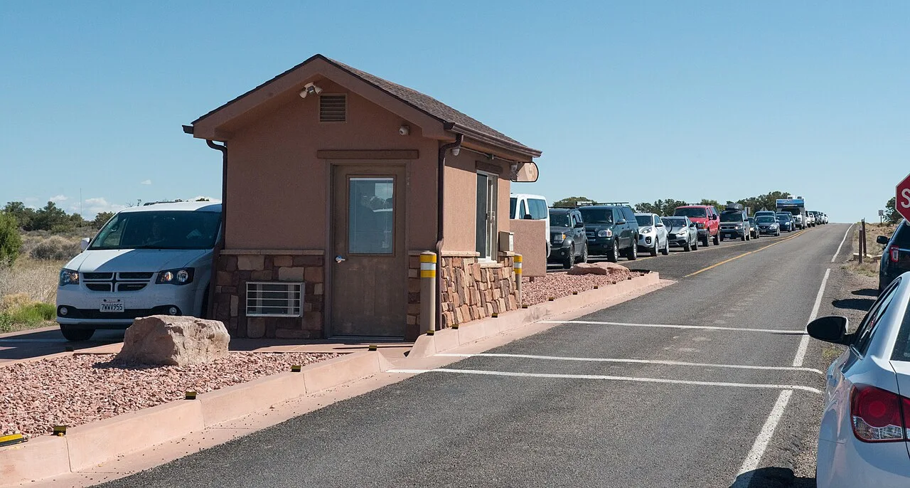 Cars lined up at a busy national park entrance station in red-rock country