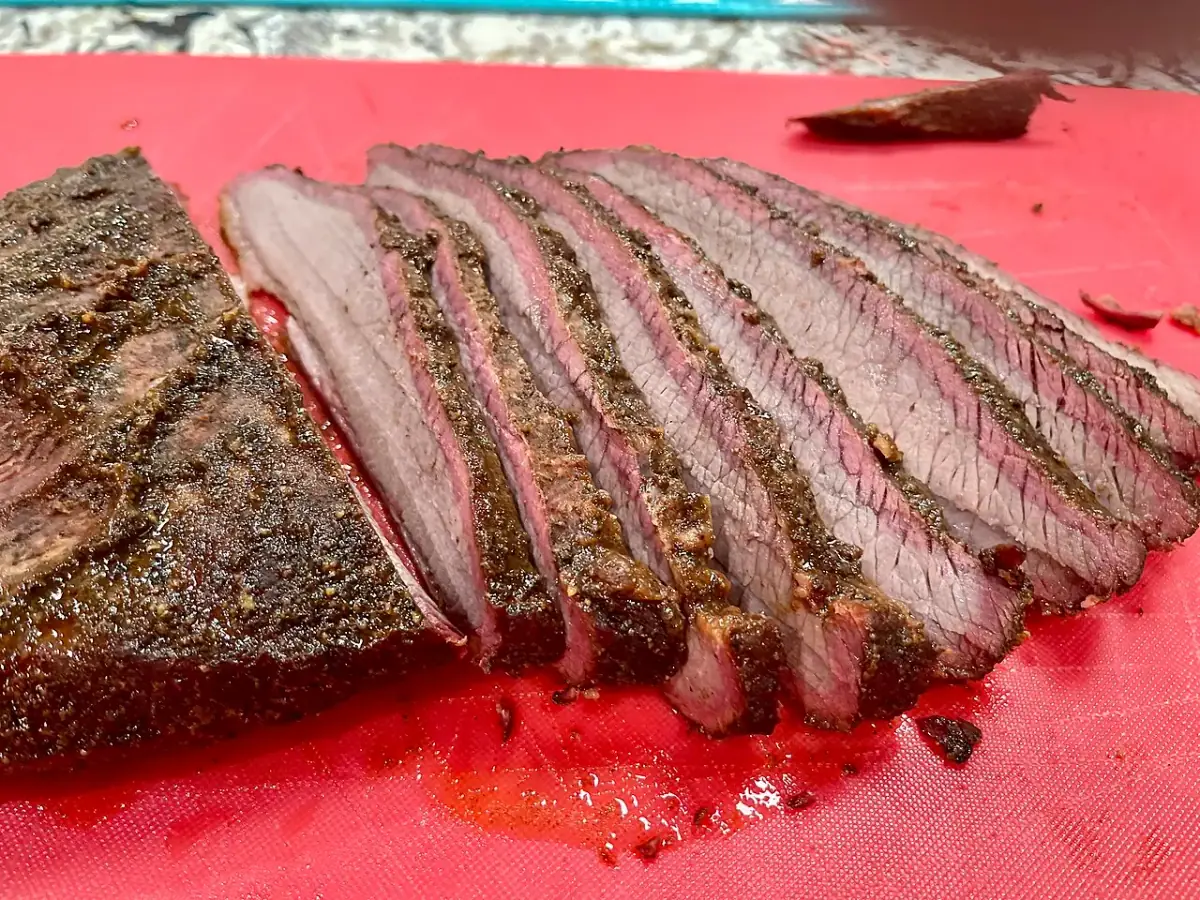 A smoked beef brisket sliced open to show the pink smoke ring and dark peppery bark