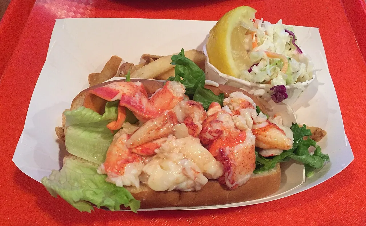 A Maine-style lobster roll in a toasted split-top bun with a side of fries