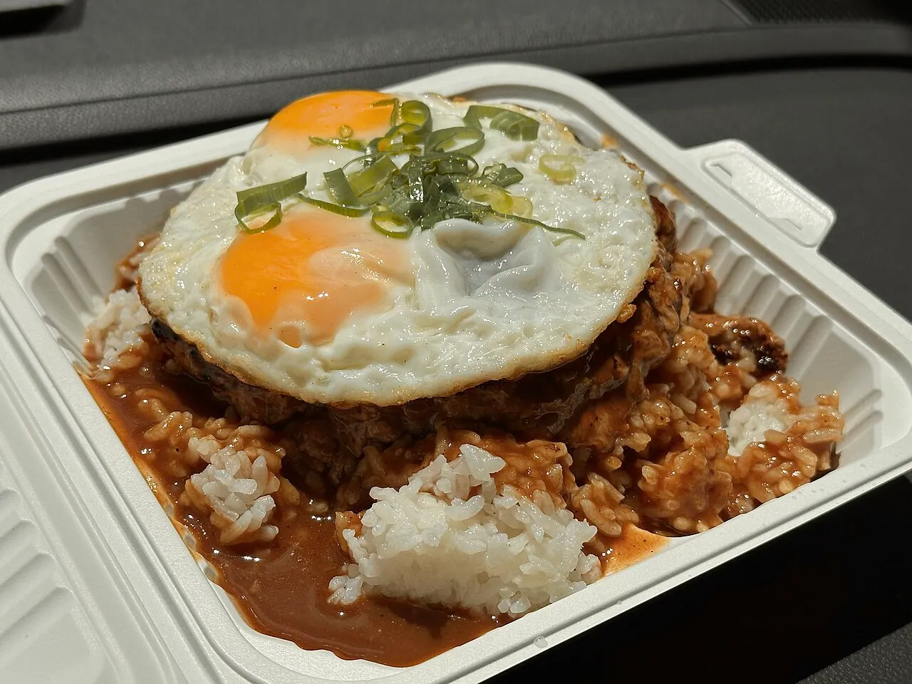 A plate of Hawaiian loco moco with hamburger patties, fried eggs, brown gravy and rice