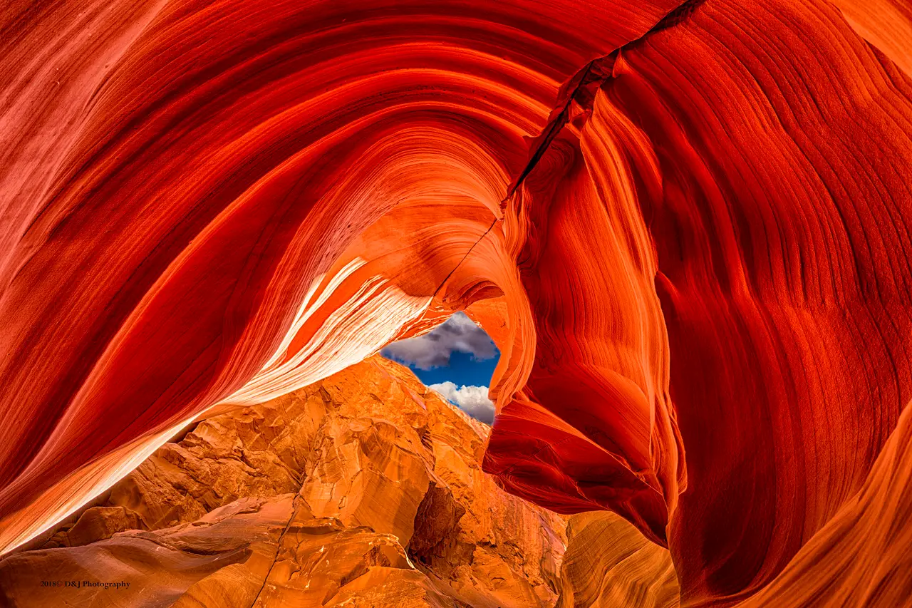 Wide sweeping sandstone walls with a patch of blue sky above at Antelope Canyon X near Page