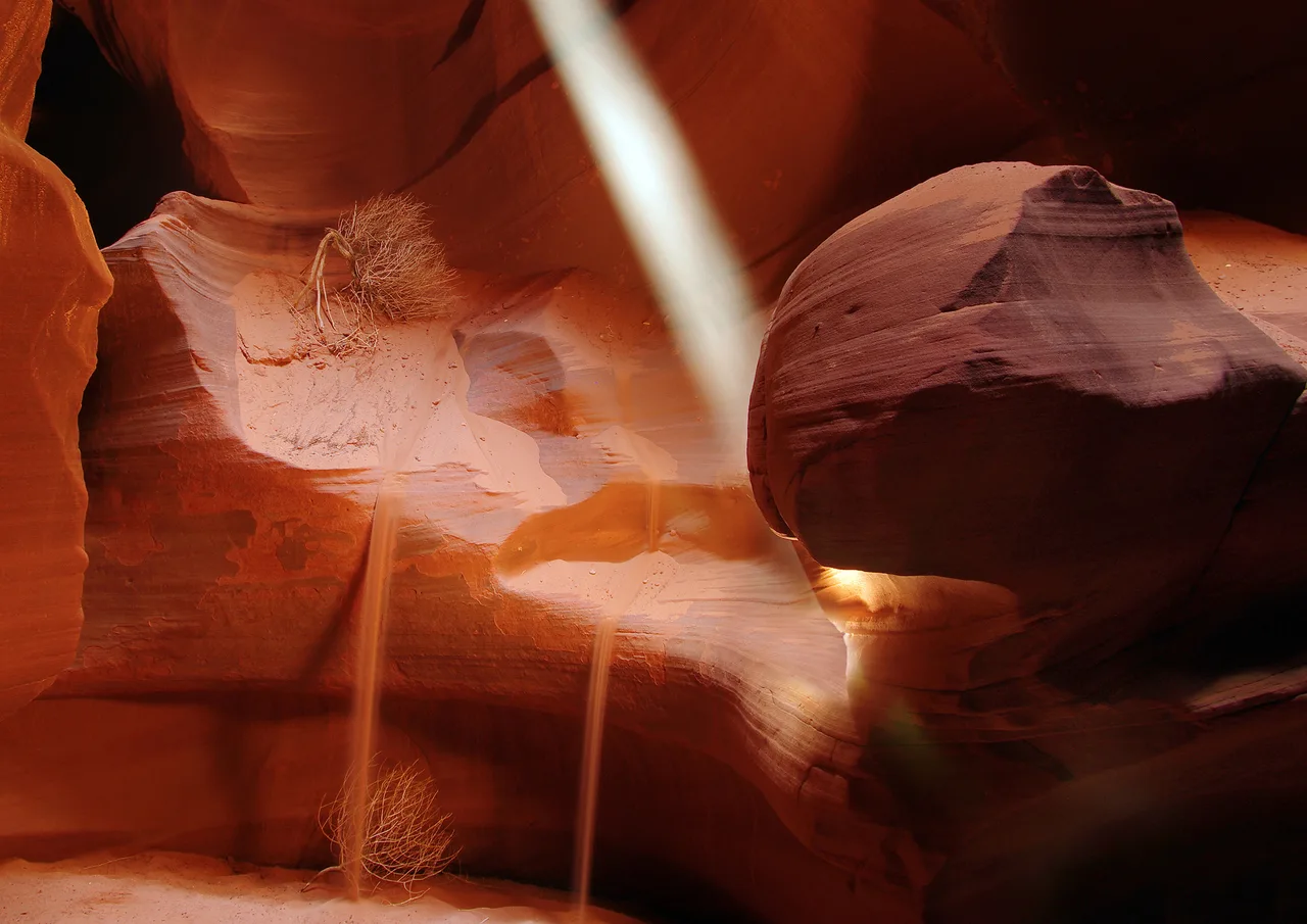 A shaft of sunlight falling through an opening onto the sand floor of Upper Antelope Canyon