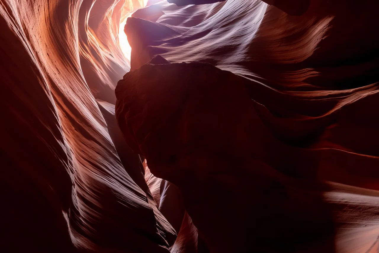 Sunlit curving sandstone walls and a narrow opening to the sky in Upper Antelope Canyon