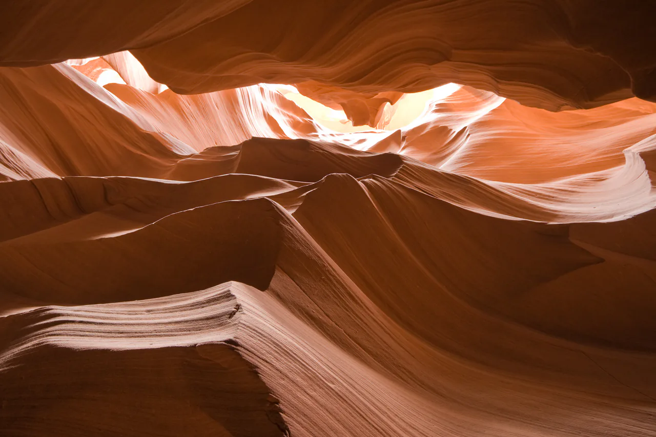 Sculpted orange sandstone walls and a shaft of light inside Upper Antelope Canyon near Page, Arizona