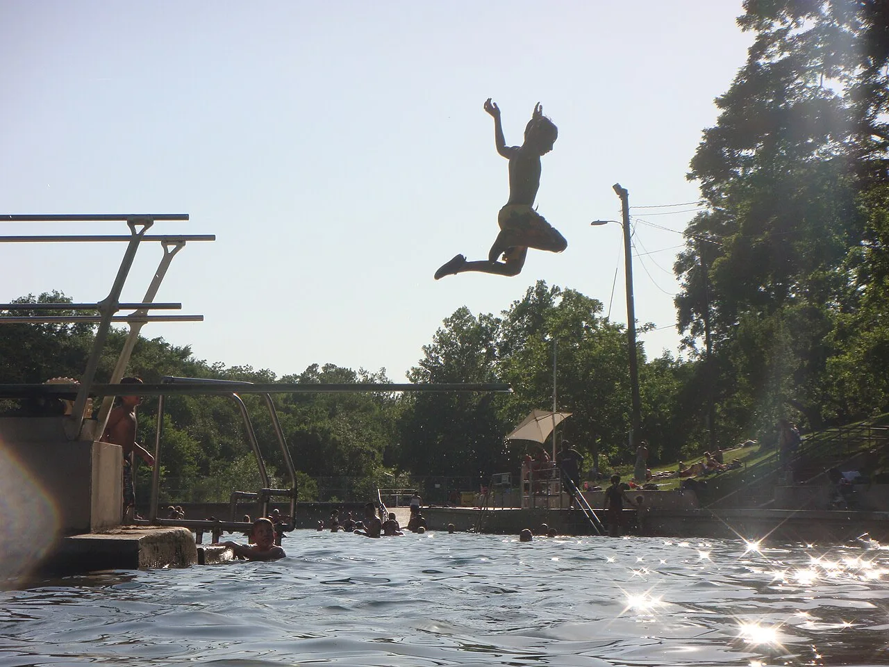 Swimmers in the long spring-fed Barton Springs Pool with grassy banks in Austin