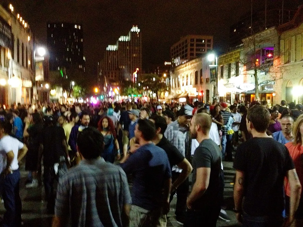Crowds and neon bar signs along Sixth Street in downtown Austin