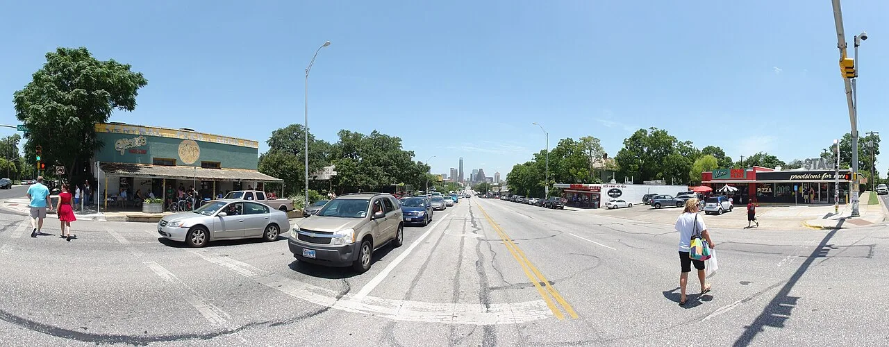 Pedestrians crossing South Congress Avenue in Austin with the Capitol dome in the distance