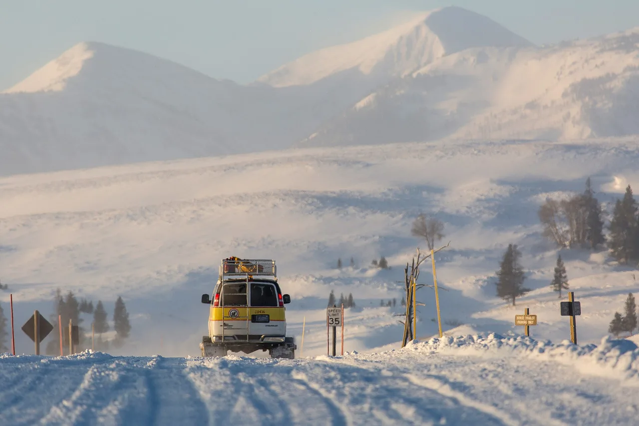 A tracked snowcoach on a snow-covered road at Swan Lake Flat in Yellowstone