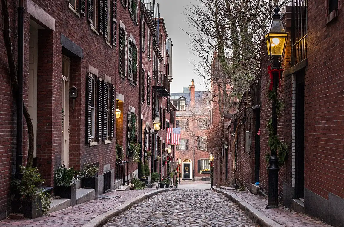 The narrow cobblestone lane of Acorn Street on Beacon Hill with brick row houses and window boxes