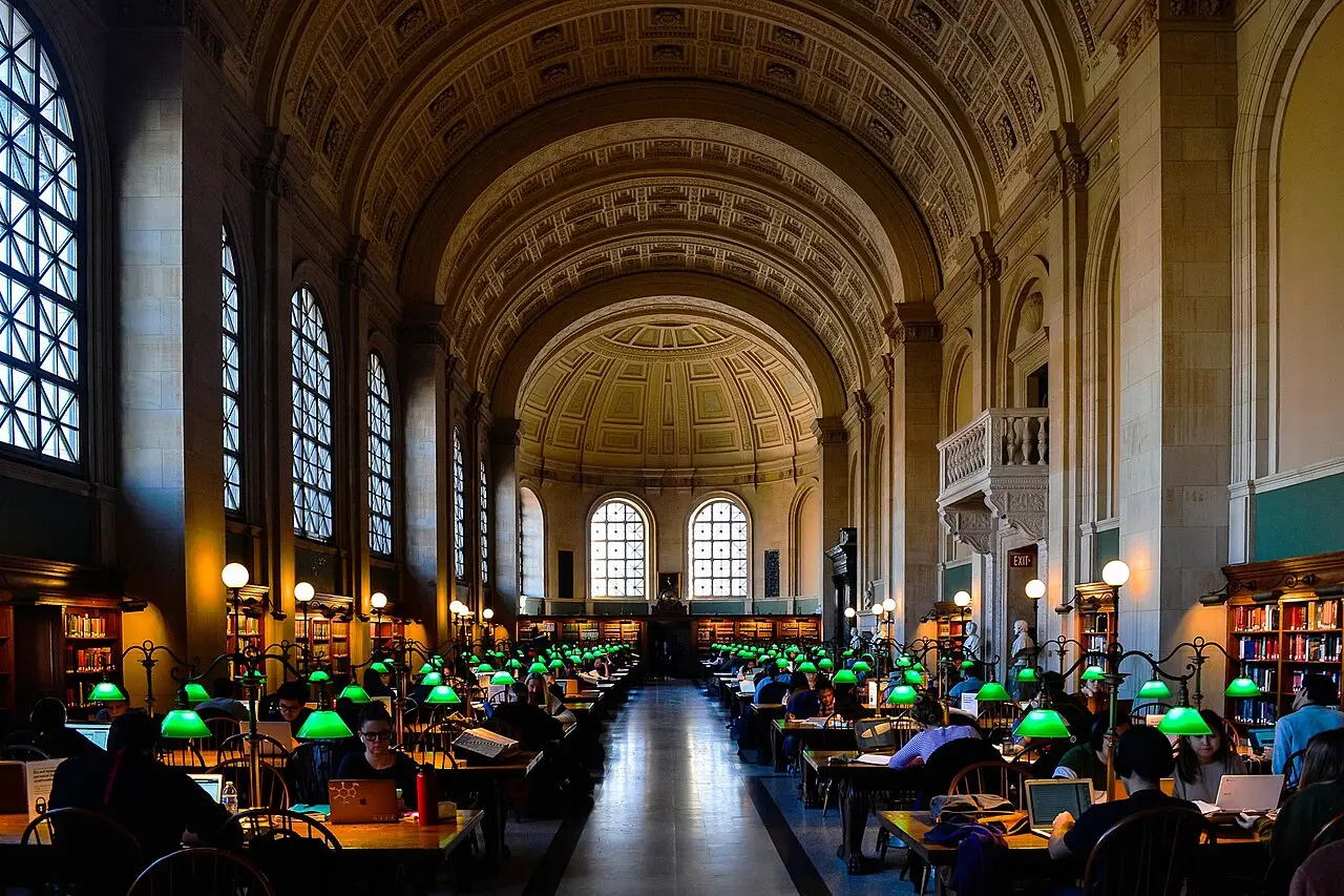 The barrel-vaulted Bates Hall reading room at the Boston Public Library with green desk lamps