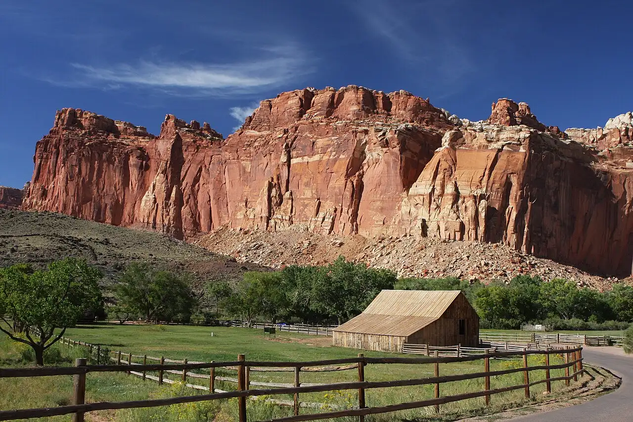 Historic Gifford barn and green orchards below red cliffs in the Fruita Historic District of Capitol Reef National Park