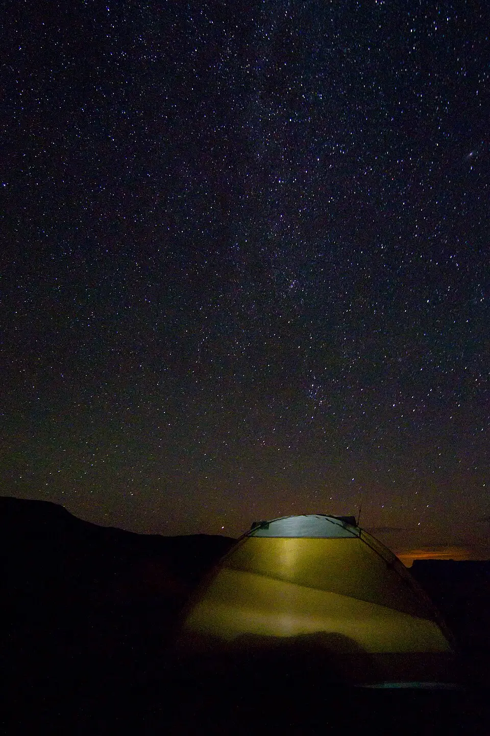 A tent illuminated at night under a star-filled sky along the White Rim Road in Canyonlands National Park