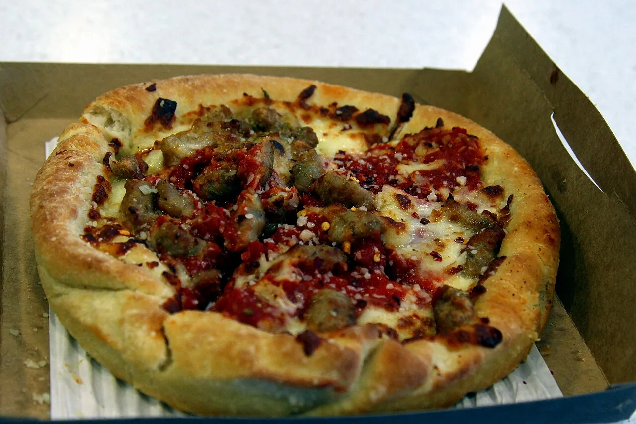 A slice of Chicago deep-dish pizza lifted from the pan, thick with cheese and tomato
