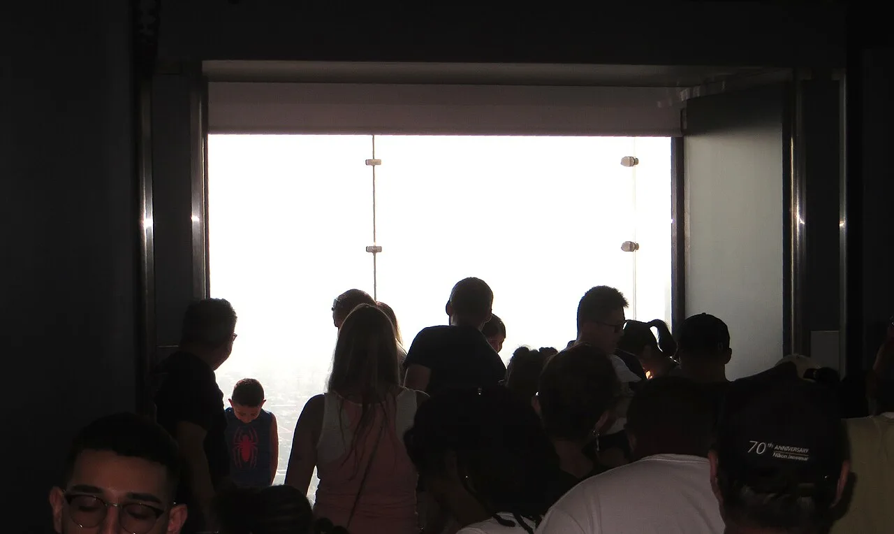 Visitors standing on the glass floor of The Ledge at the Willis Tower Skydeck looking down at Chicago