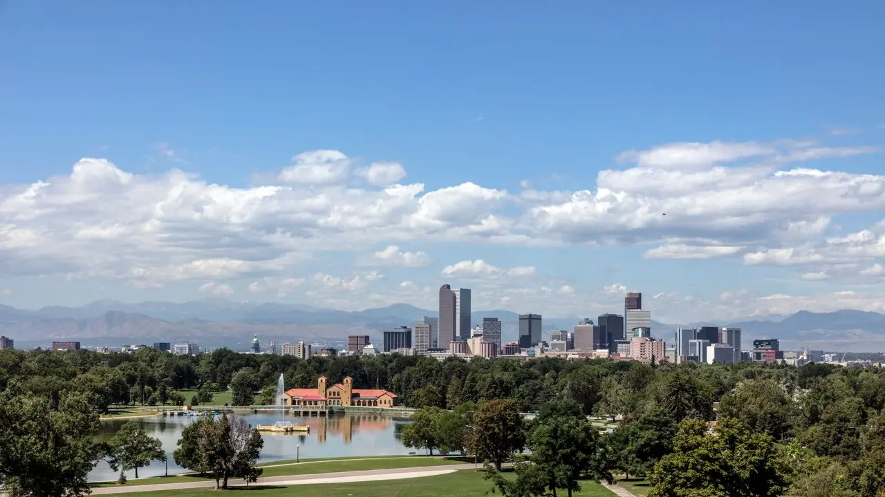 The Denver skyline seen across Ferril Lake in City Park with the Rocky Mountains behind