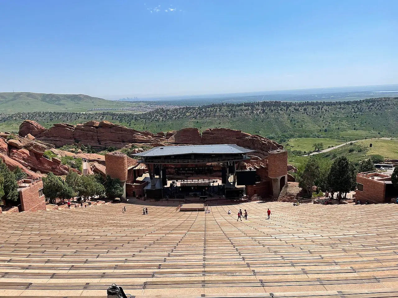 The empty seating bowl of Red Rocks Amphitheatre with the Denver skyline on the horizon