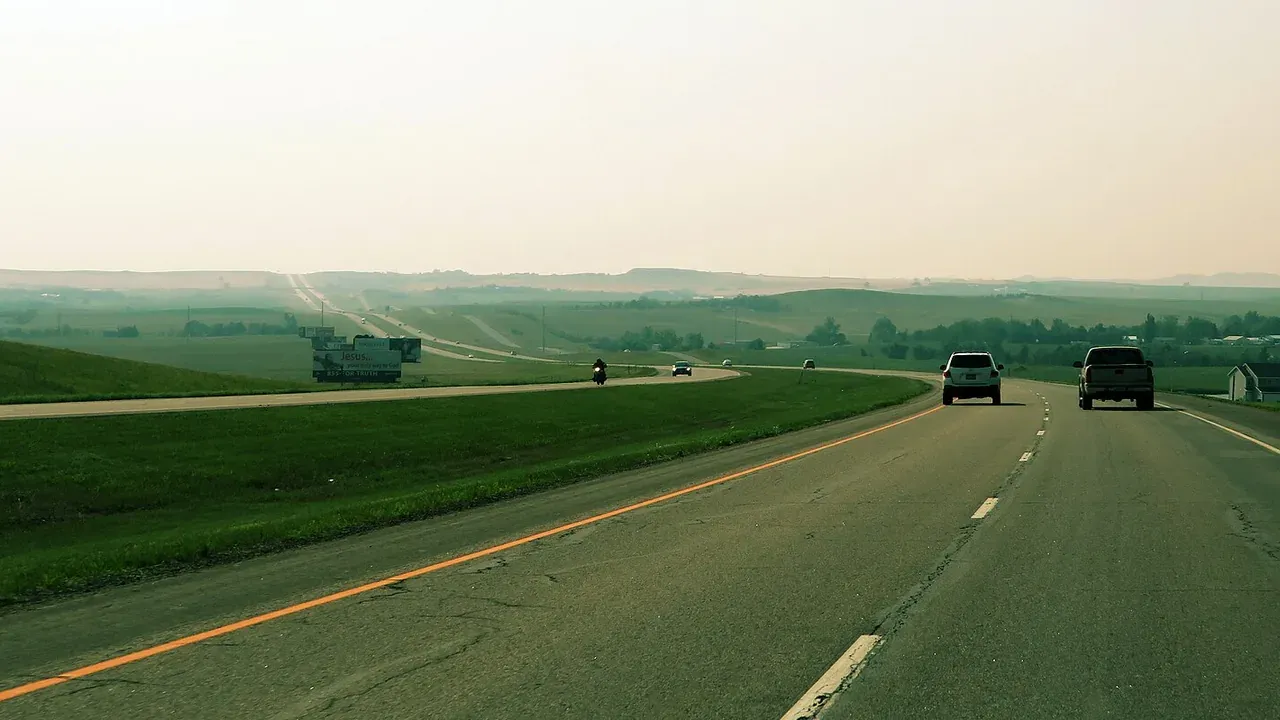 Open interstate highway cutting through prairie under a wide North Dakota sky