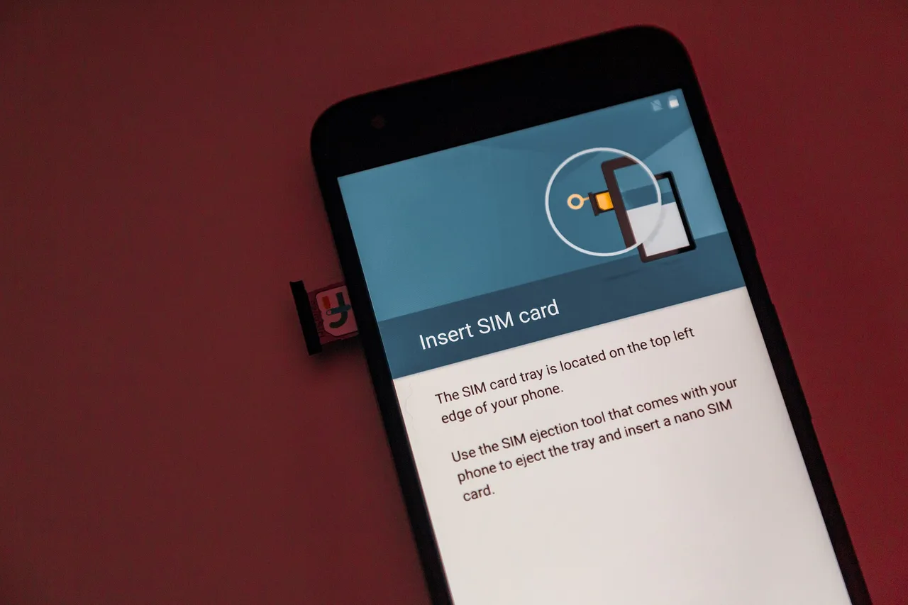 A SIM card being inserted into the partially ejected tray of an Android smartphone