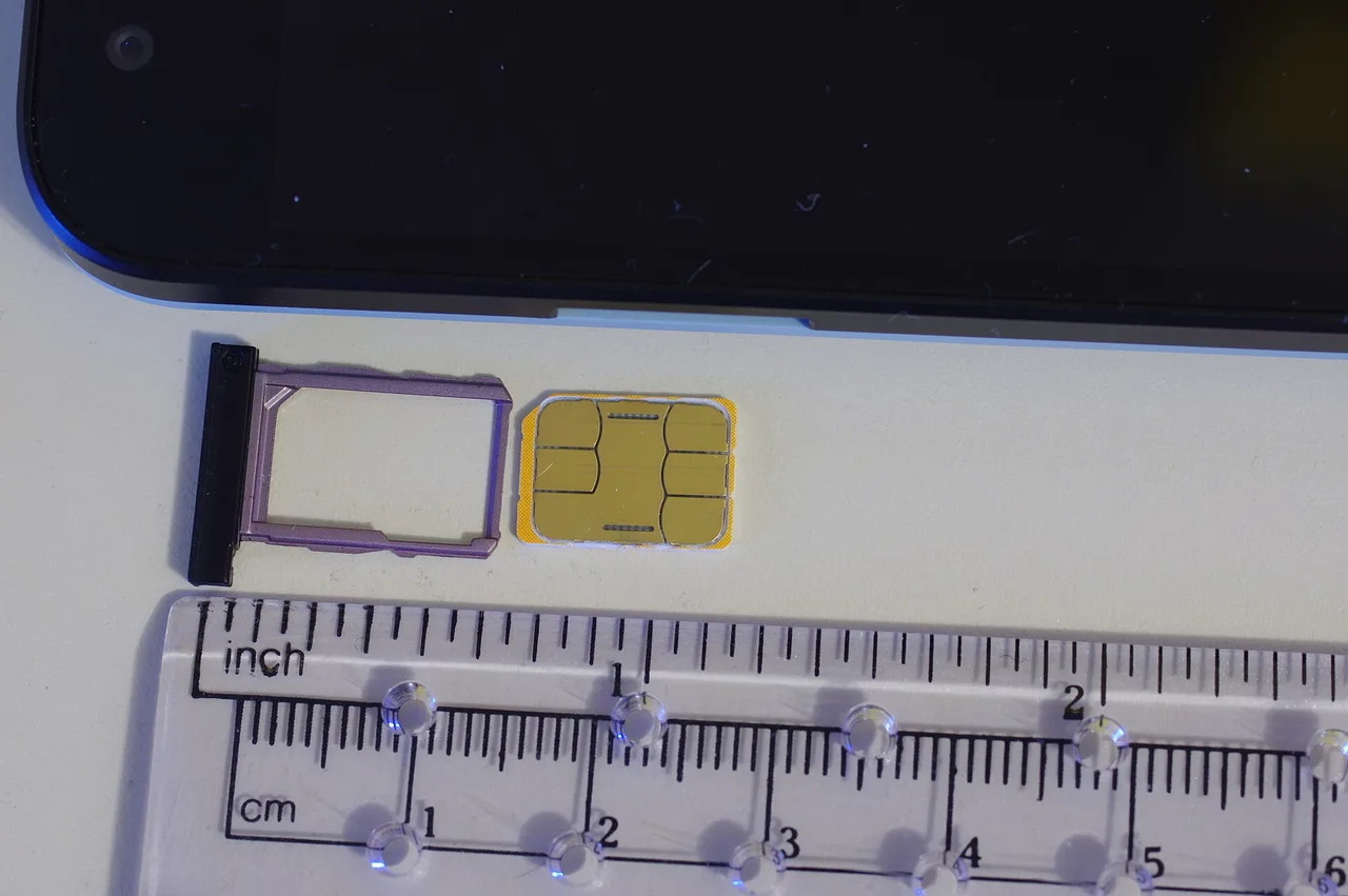 A nano SIM card next to its ejected tray from a smartphone