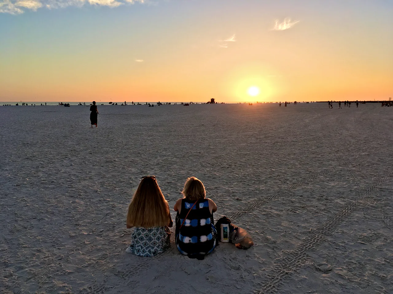People watching the sunset from the wide white sand of Siesta Beach on the Gulf coast