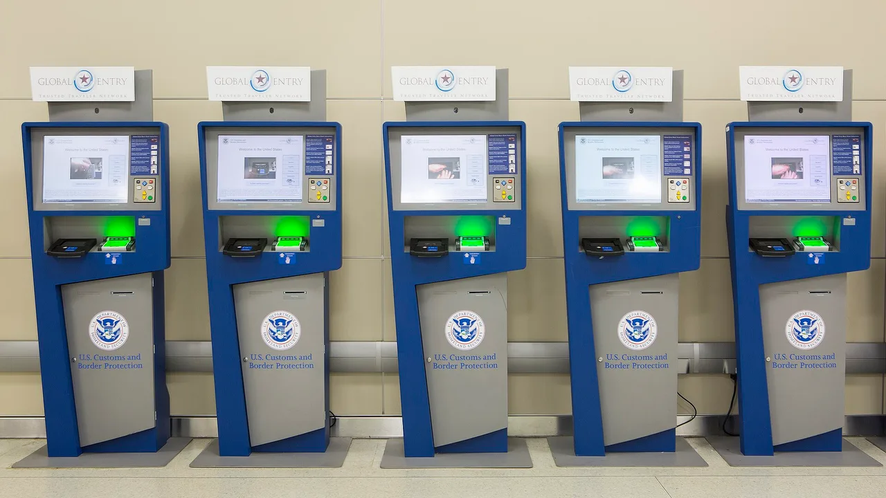 A row of Global Entry kiosks with Trusted Traveler Network signs in a US airport arrivals hall