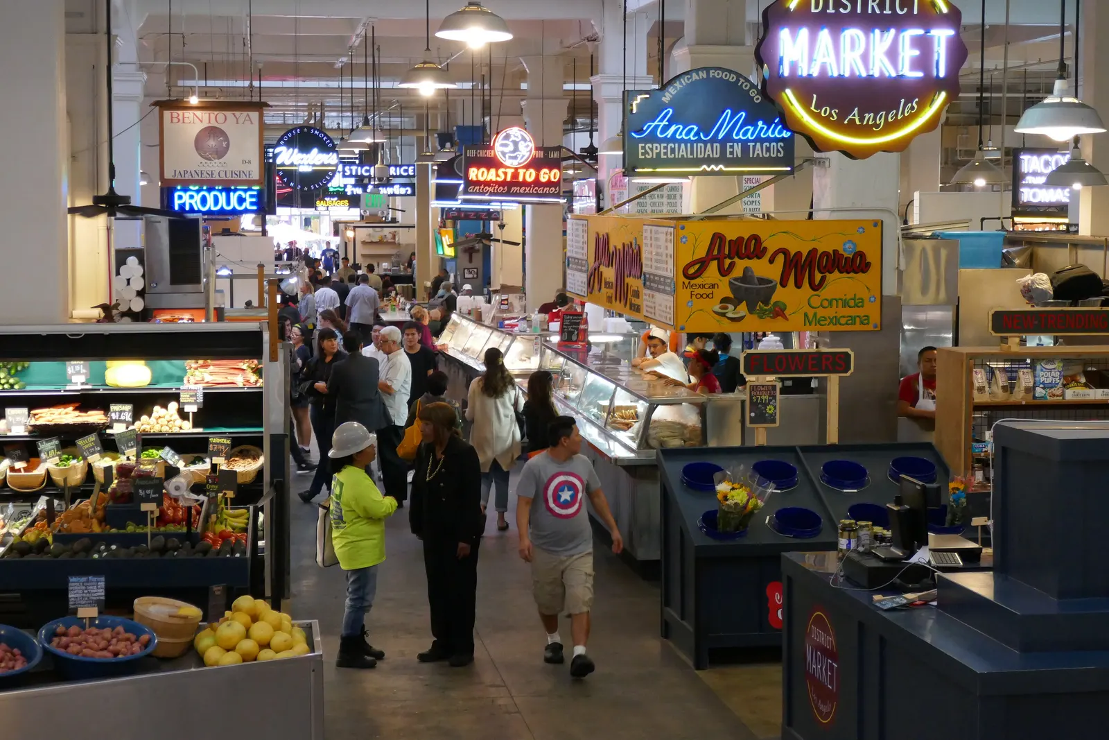 Crowded aisle of food stalls under neon signs inside the historic Grand Central Market in downtown Los Angeles
