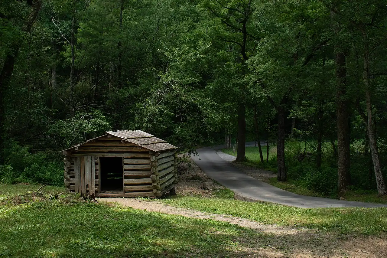 Restored log cabin with a stone chimney at Tipton Place in Cades Cove