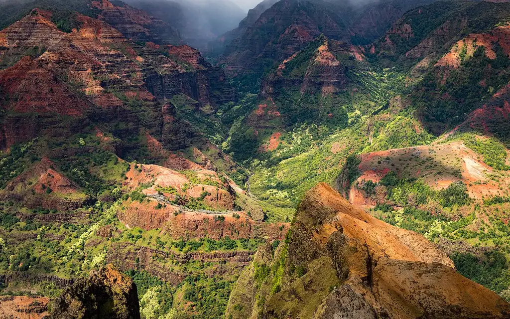 The red and green walls of Waimea Canyon on Kauai under scattered cloud