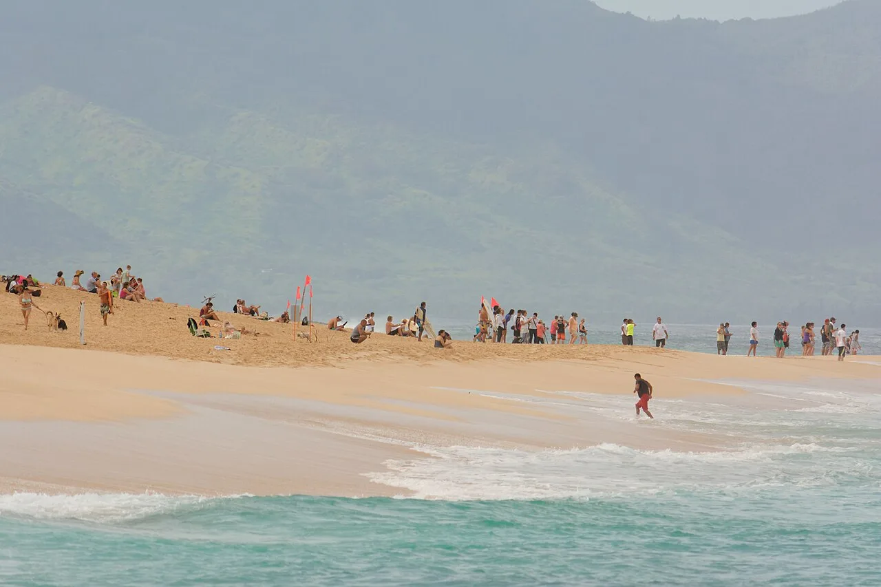 Surf breaking at Banzai Pipeline on Oahu's North Shore with spectators on the sand