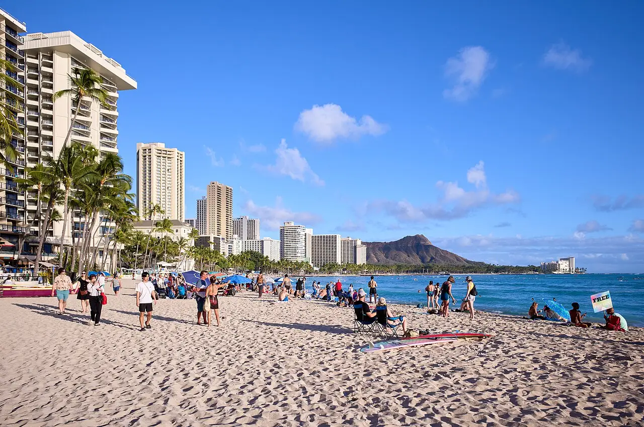 Sunbathers and surfers on Waikiki Beach with hotel towers behind