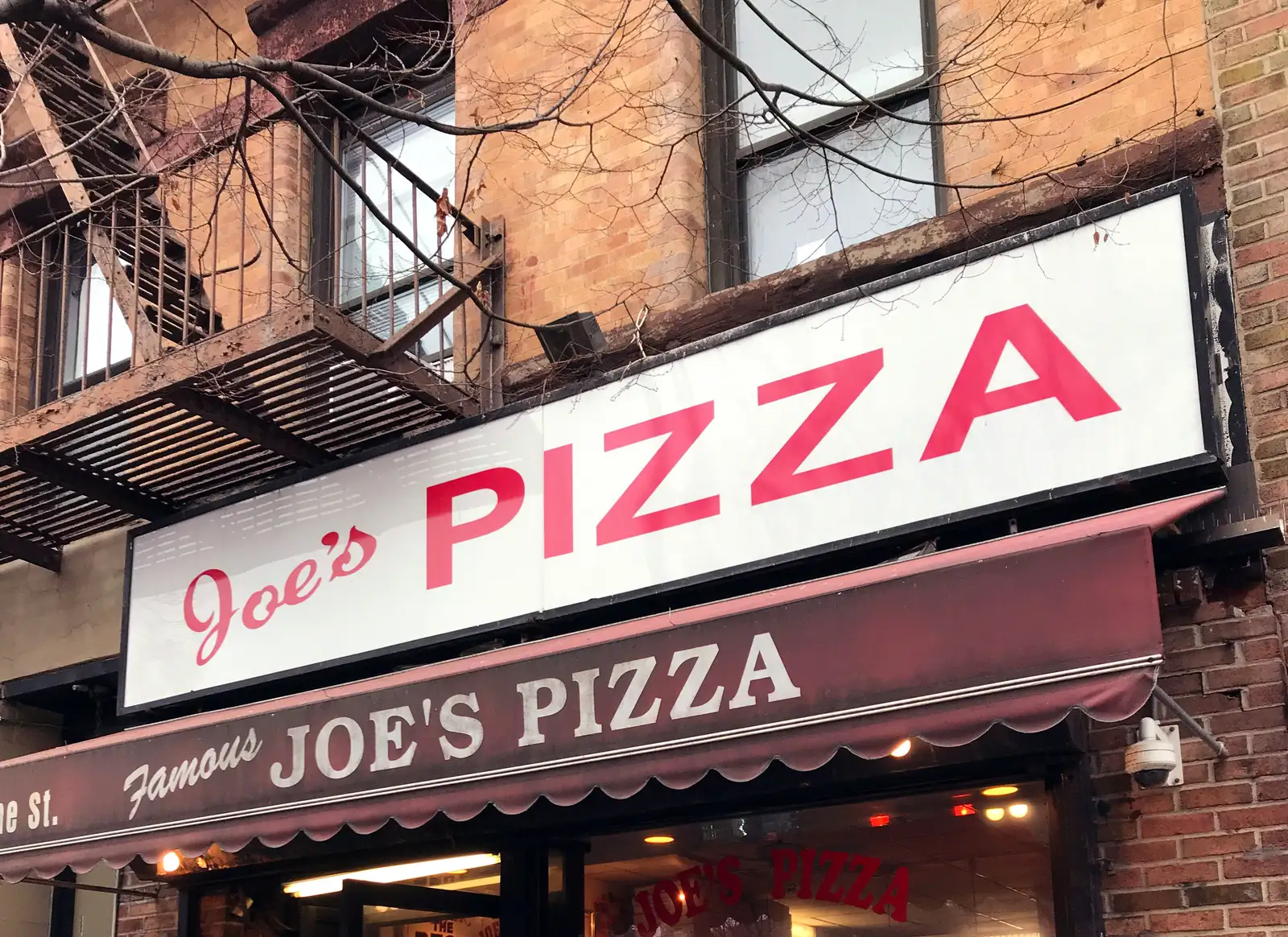 The illuminated Joe's Pizza storefront sign and awning on Carmine Street in Greenwich Village