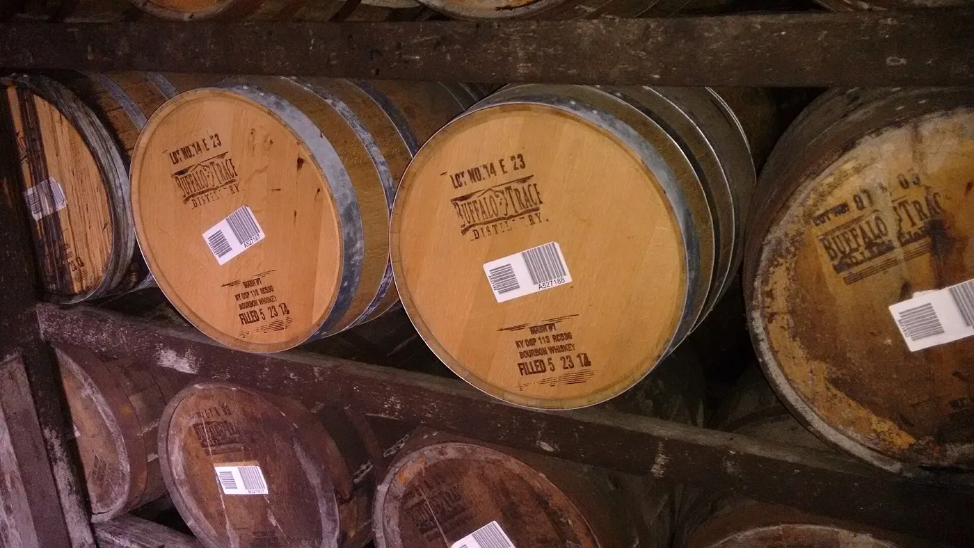 Rows of stacked oak bourbon barrels inside a Kentucky distillery warehouse