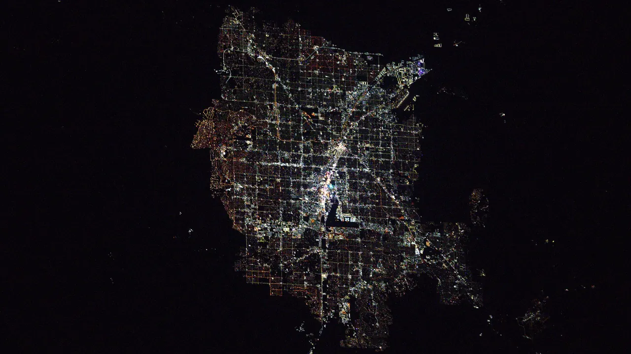 Nighttime satellite view of the Las Vegas Strip glowing beside Harry Reid International Airport