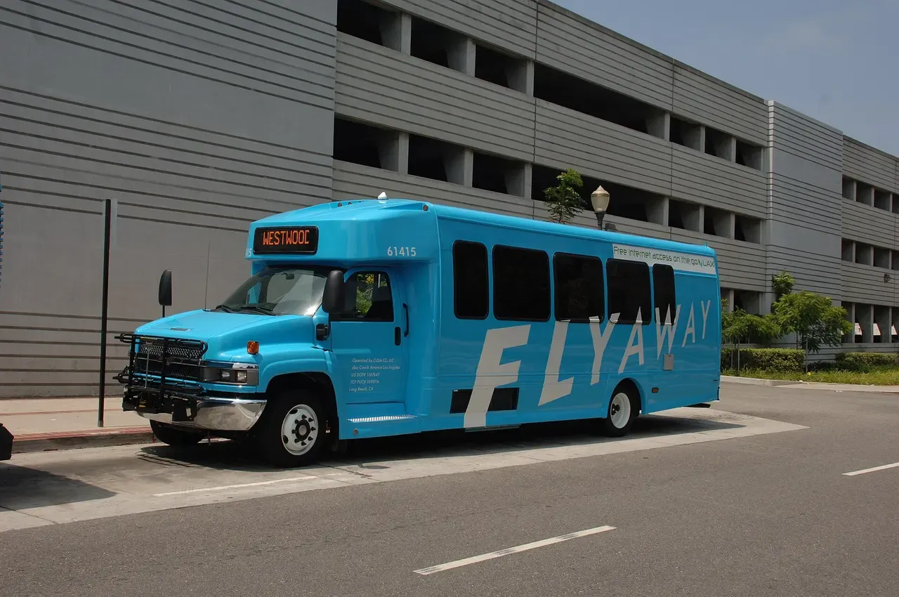 A white LAX FlyAway compressed-natural-gas bus parked at a curb