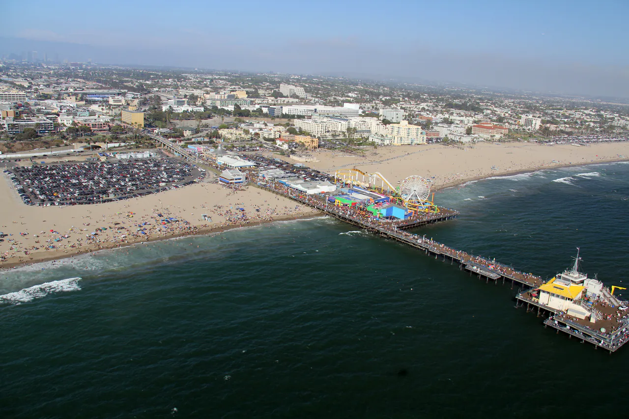Santa Monica beach and pier seen along the sand with the Ferris wheel on the pier
