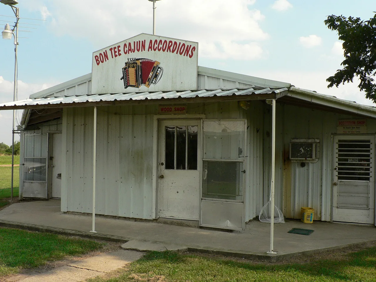 A small metal building in rural Louisiana with a hand-painted Bon Tee Cajun Accordions sign