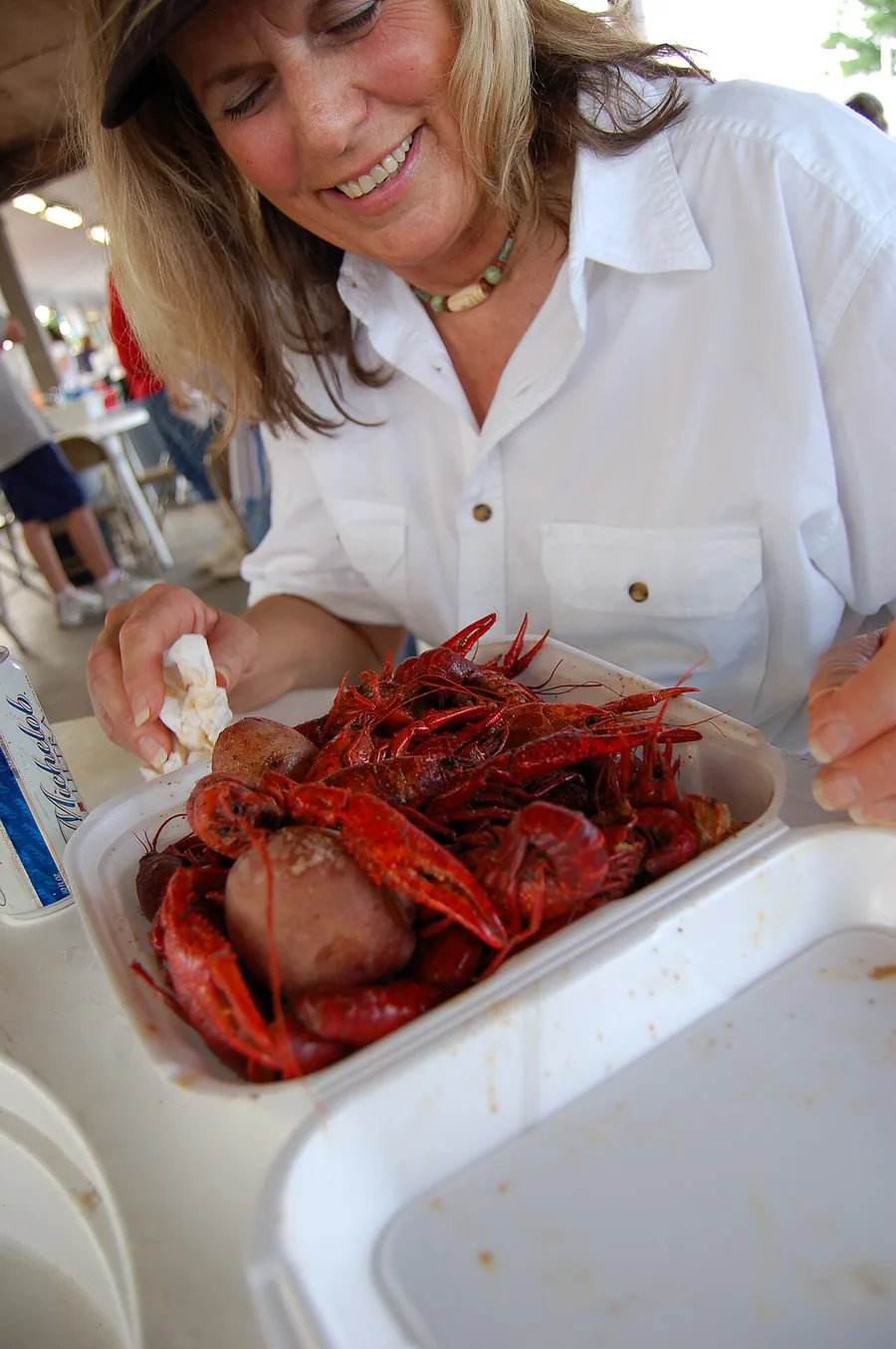 A woman leaning over a tray of boiled crawfish and potatoes at the Breaux Bridge crawfish festival