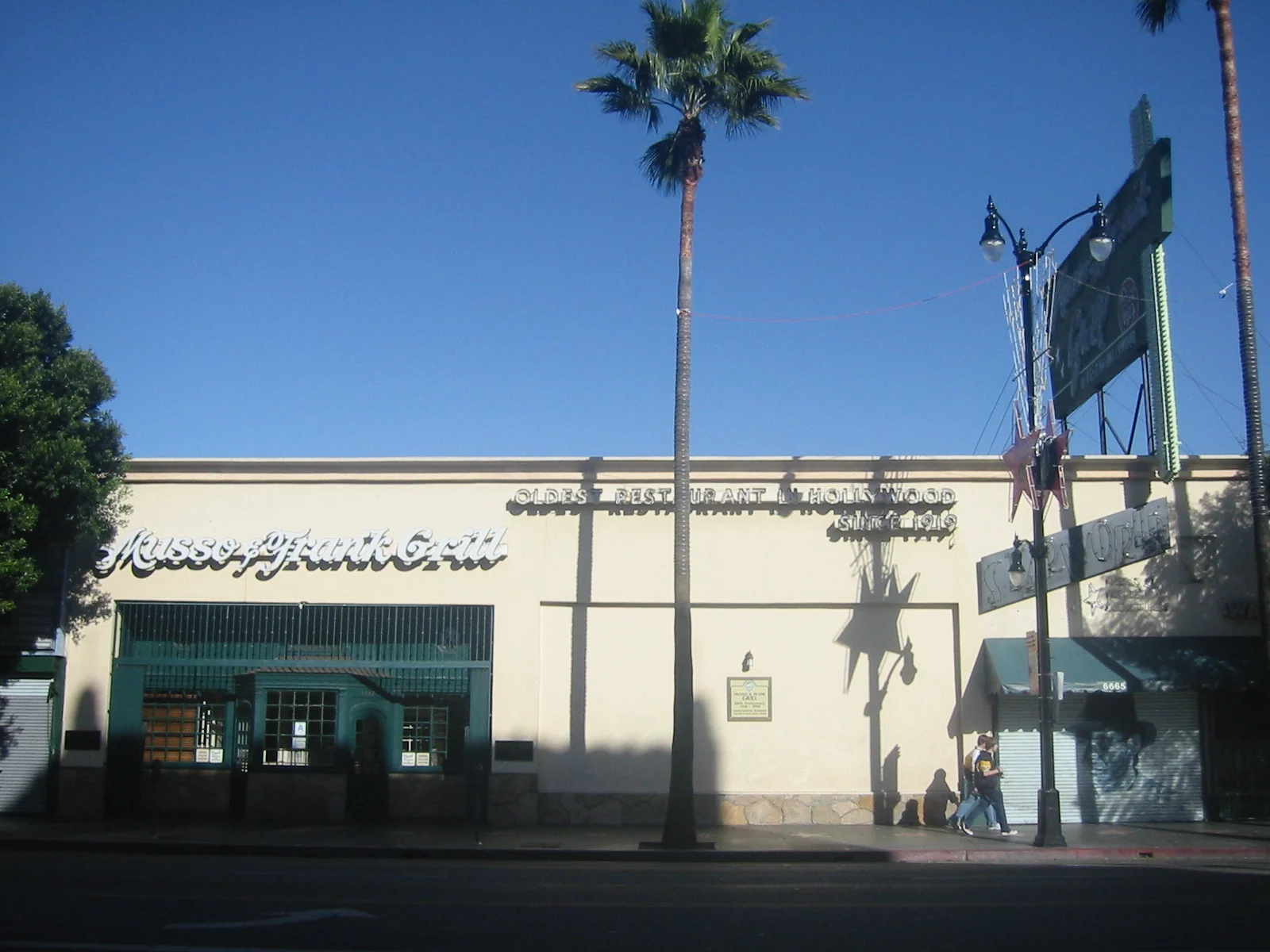 Musso & Frank Grill's cream-colored facade on Hollywood Boulevard with its painted 'Oldest Restaurant in Hollywood' sign