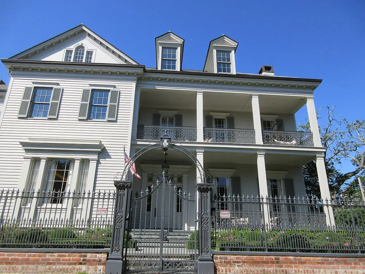 A columned 19th-century mansion behind an iron fence in the Garden District of New Orleans
