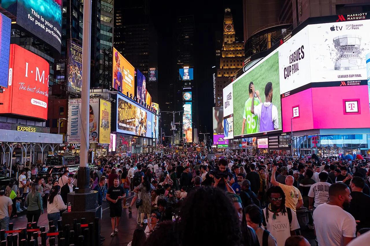 Times Square at night lit by giant advertising screens with crowds below