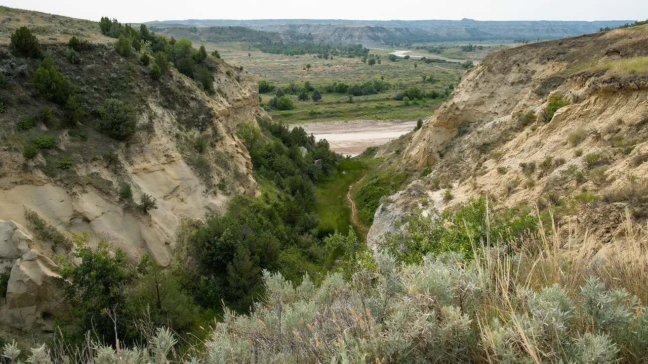 Layered badlands and prairie under open sky in Theodore Roosevelt National Park