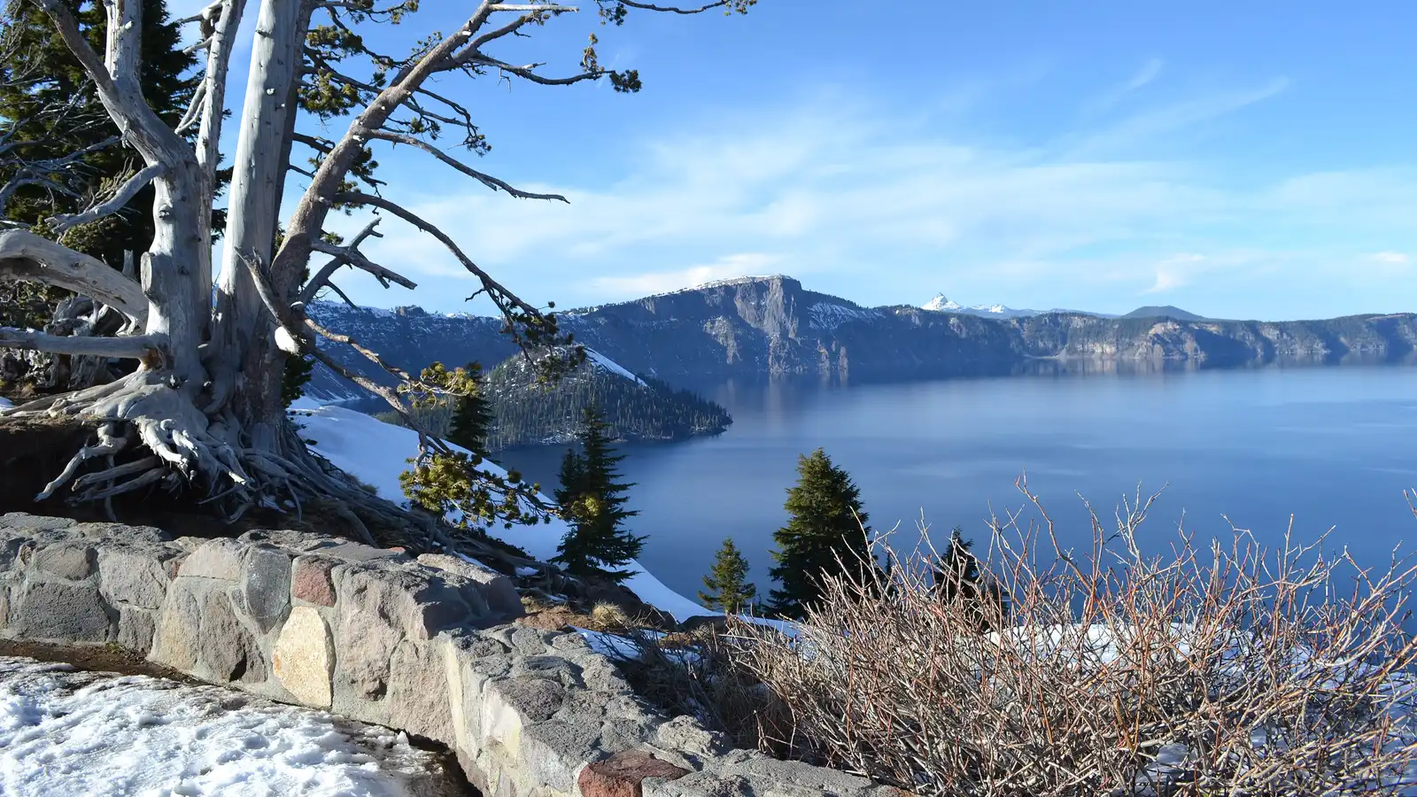 Crater Lake with Wizard Island rising from deep blue water and snow along the caldera rim