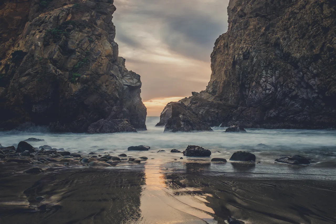 Waves breaking through the rock arch at Pfeiffer Beach in Big Sur at dusk