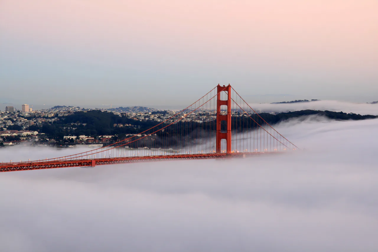 The Golden Gate Bridge in evening light with fog drifting around the towers
