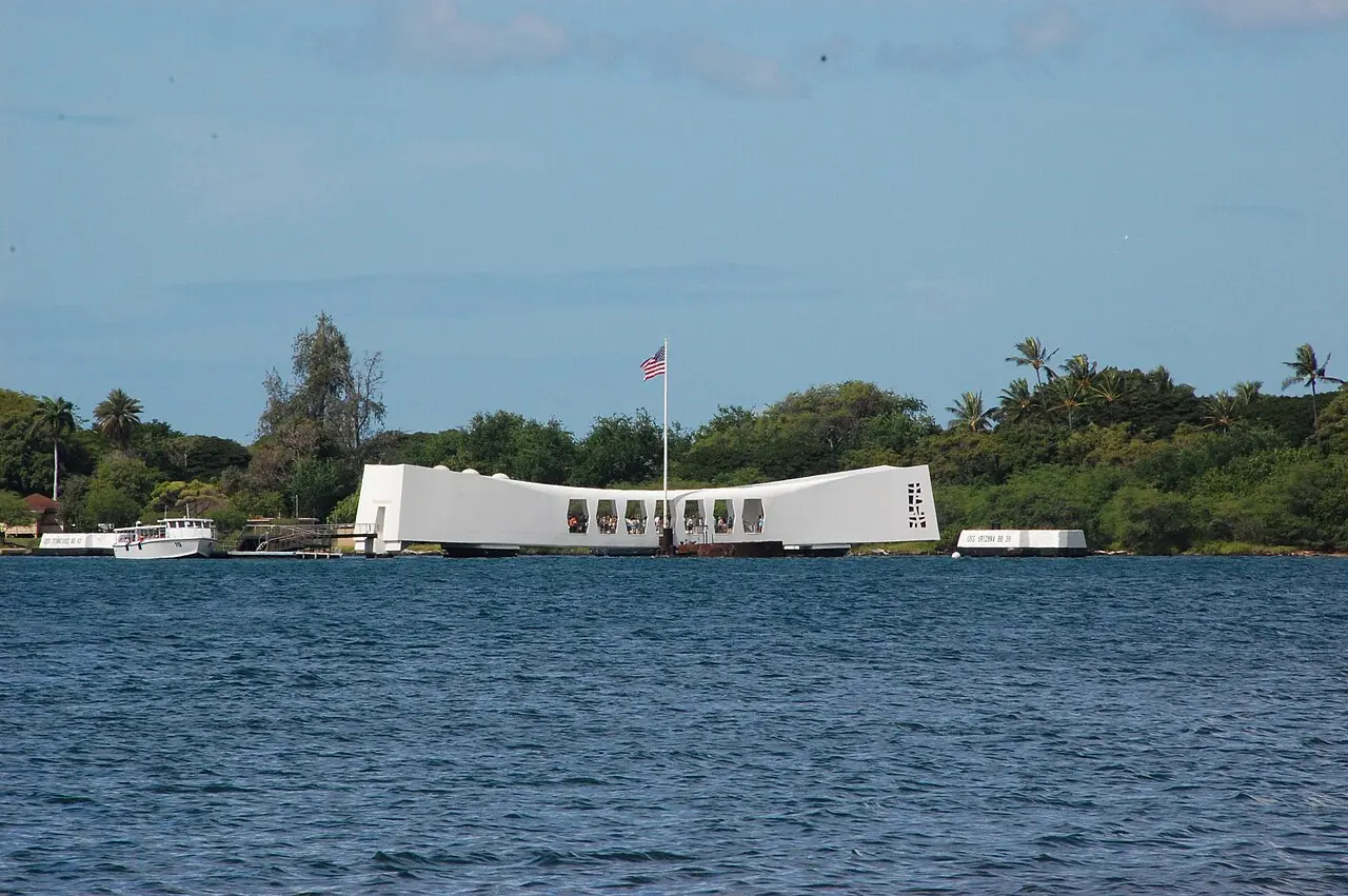 White Navy shuttle boat docked at the USS Arizona Memorial with visitors visible inside the open structure
