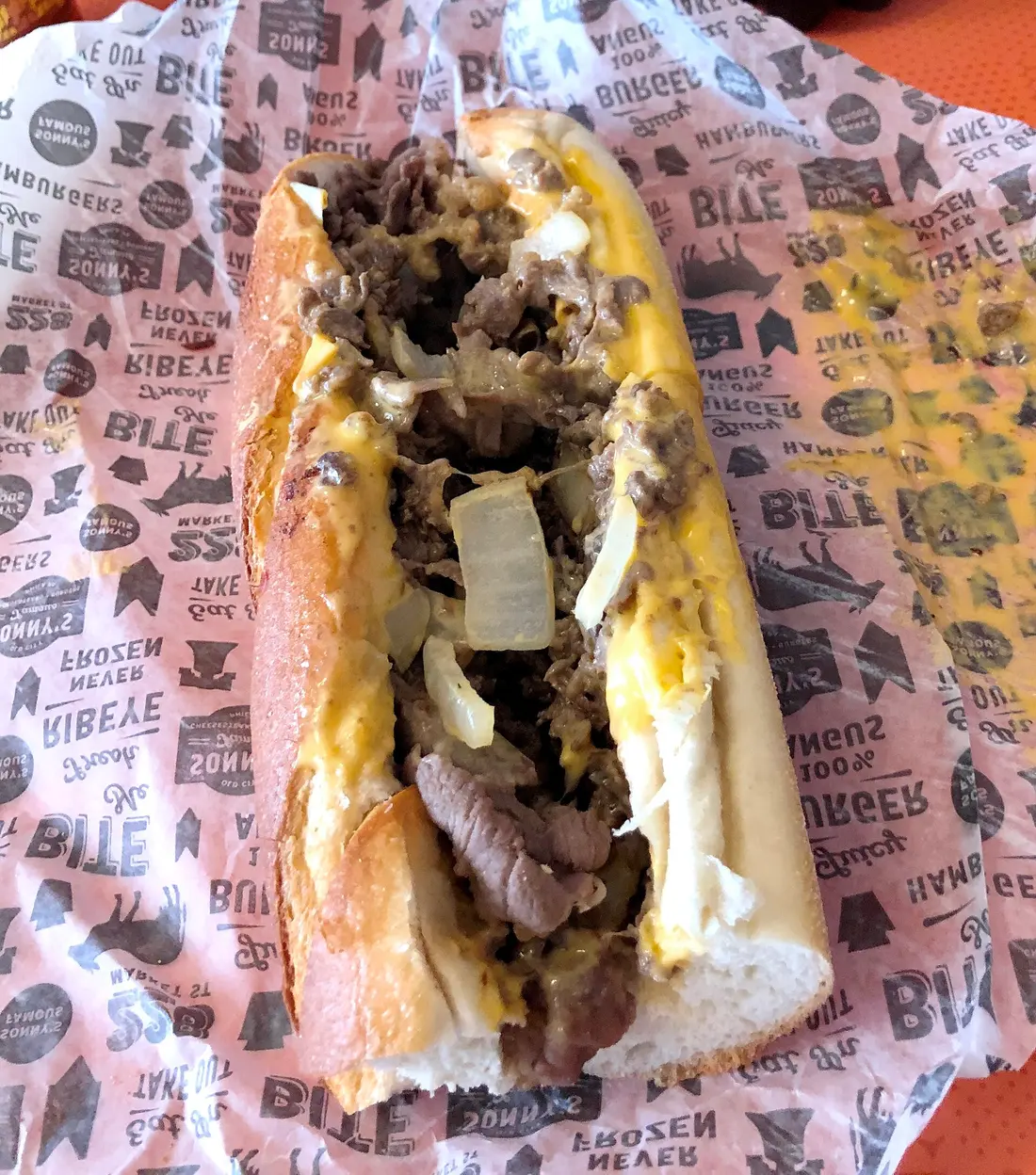 A Philadelphia cheesesteak on a long roll with melted cheese and fried onions